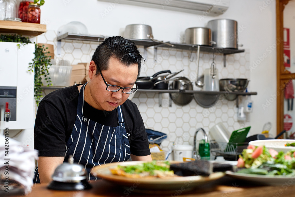 Asian chef working in kitchen at organic food cafe Asian chef working in kitchen at organic food cafe