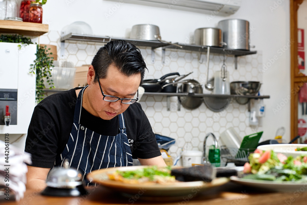 Asian chef working in kitchen at organic food cafe Asian chef working in kitchen at organic food cafe