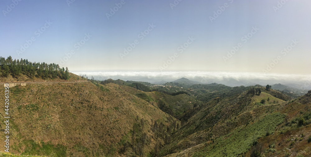 Panoramic photo of a mountainous landscape in the interior of Gran Canaria with a sea of ​​clouds in the background.