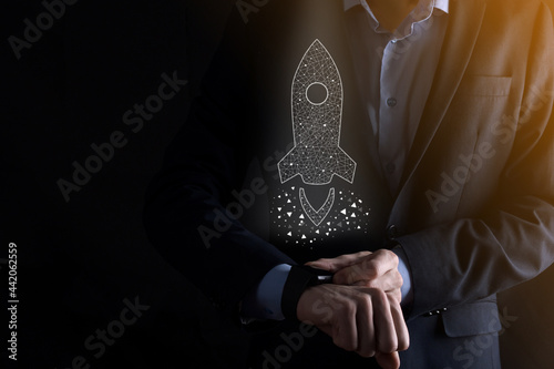 Startup business concept, Businessman holding icon transparent rocket is launching and soar flying out from screen with network connection on dark background.