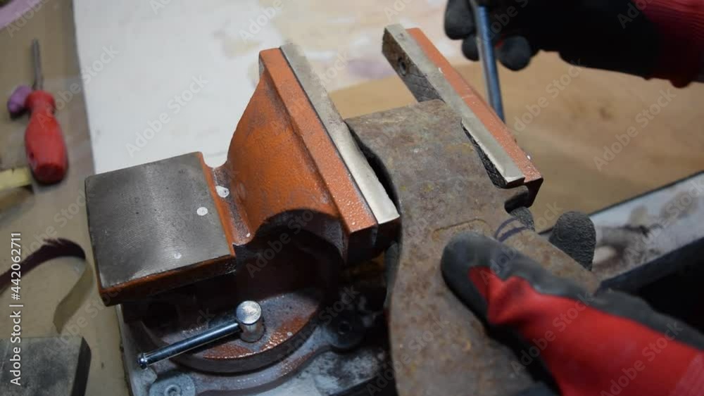A worker clamps a part of the axe in a vise for processing. A worker clamps a part of the axe in a vise for processing.
