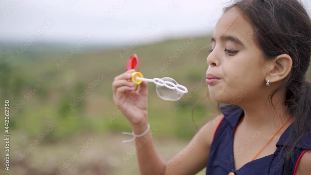 Young girl kid playing by blowing soap water bubbles - conept of playful chidlren during holiday vacation Young girl kid playing by blowing soap water bubbles - conept of playful chidlren during holiday vacation