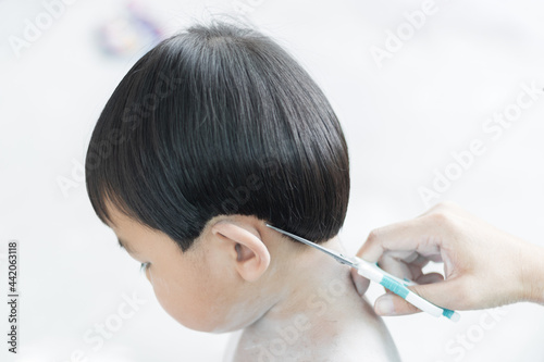 A cute asian young boy getting a haircut at home.