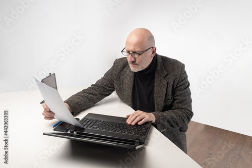 Office worker with laptop. Portrait of an office worker sitting at the table. An adult man in a business suit. Top view businessman portrait. Office worker on the background of white walls