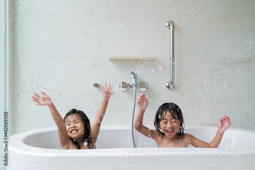 фотографія two happy asian girl taking a bath together on a bathtub