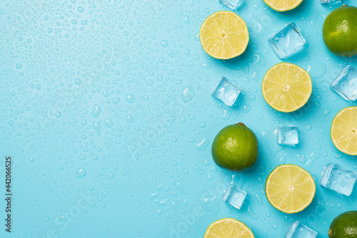 Above photo of heap of limes cubes of ice and drops isolated on the blue background with empty space