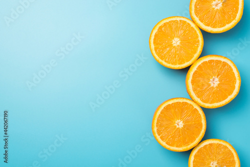 Top view photo of orange slices in vertical winding line on the right on isolated pastel blue background with copyspace on the left
