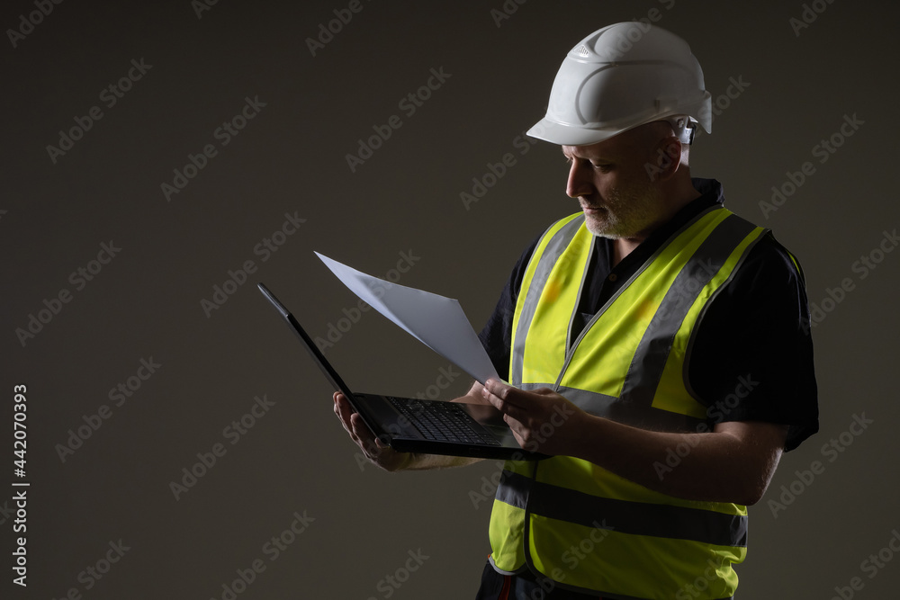 An architect or engineer with a laptop and drawings. The construction engineer clarifies the details of the project. Technical specialist with a laptop. An engineer in a white helmet. An architect or engineer with a laptop and drawings. The construction engineer clarifies the details of the project. Technical specialist with a laptop. An engineer in a white helmet.