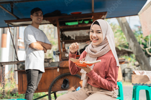 muslim woman ordering chicken satay from small food cart seller. sate ayam street food