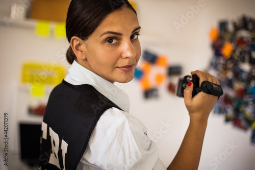 FBI woman works on a case. Using camera. Looking at camera.