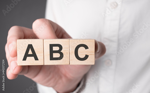 Business man hand holding wooden cube with abc text. Financial, marketing and business concepts photo