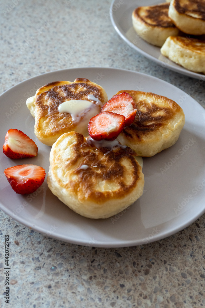fluffy pancakes on a plate are stuffed with strawberries and poured with jam. thick pancakes for breakfast fluffy pancakes on a plate are stuffed with strawberries and poured with jam. thick pancakes for breakfast
