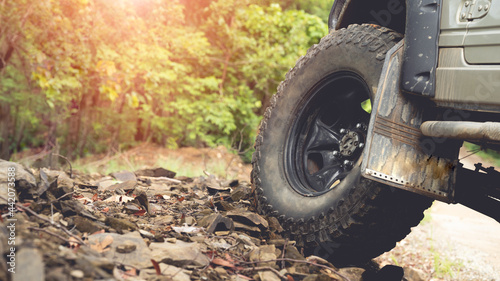 Part of an off-road vehicle on a dirt road with warm light. Adventure concept.Tire off-road on mud