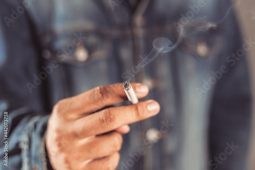 man holding smoking a cigarette in hand. Cigarette smoke spread.