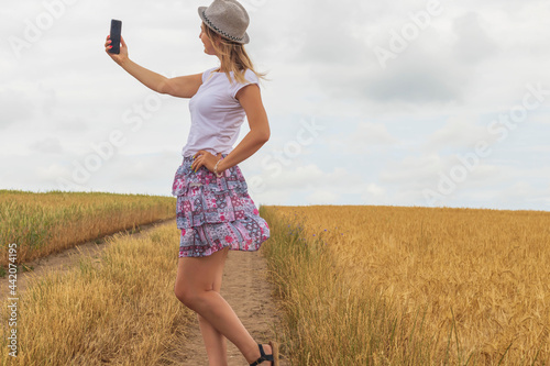 Young girl taking a selfie on the background of a wheat field photo