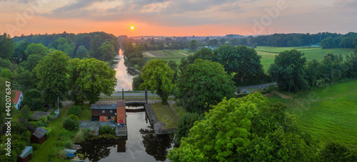Summer sunset over river in countryside landscape. Lock at Kluvensiek of the Old Eider Canal, predecessor of the Kiel Canal. Eider River at Kluvensiek. photo