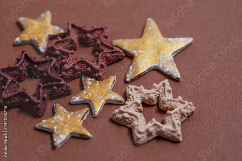 Gold and chocolate stars on a brown craft background. Handmade polymer clay miniatures. 