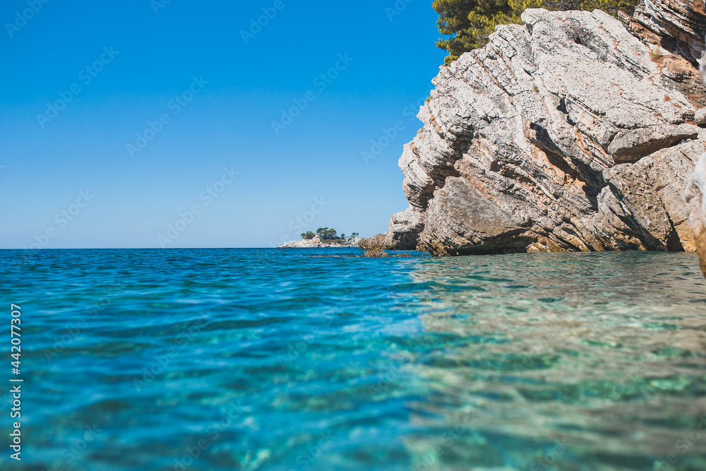 View from the water level to the steep coastal cliffs of the coast of the sea lagoon - turquoise clear water