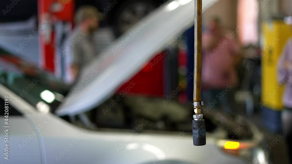 A day in the mechanic’s garage as people friends and family stand around broken broke down car chatting and talking in the shop, as focus is on compressed air hose hanging. In 4k 60 FPS real time.