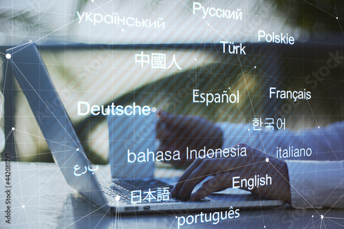 Side view of businessman at desktop with coffee cup using cellphone and laptop with creative digital languages mesh on blurry background. Online dictionary and translation concept. Double exposure.