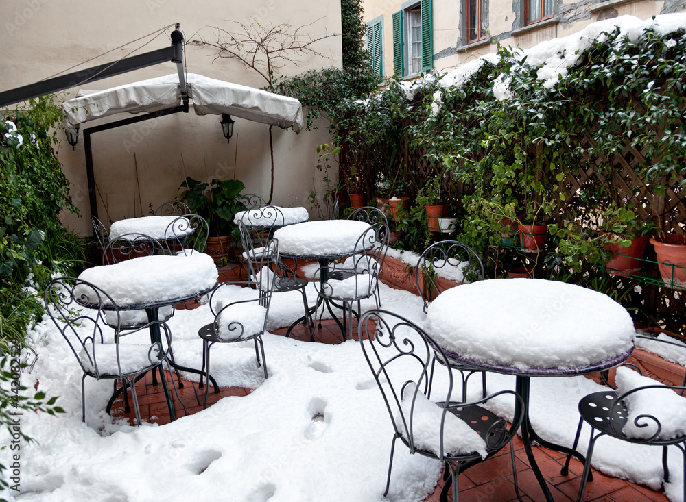 Tables and chairs covered in deep snow.