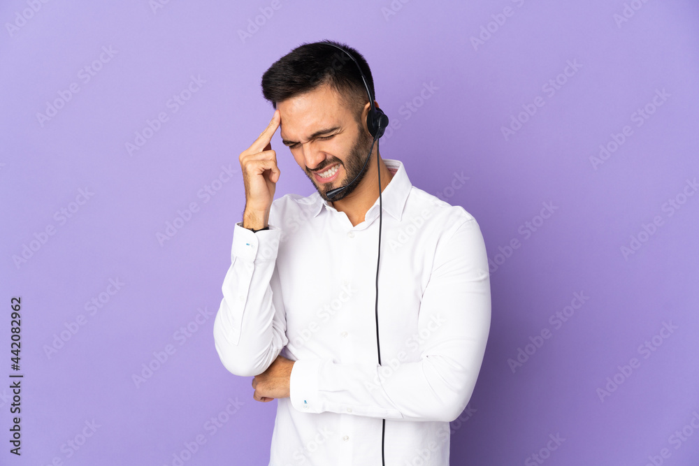 Telemarketer man working with a headset isolated on purple background with headache Telemarketer man working with a headset isolated on purple background with headache