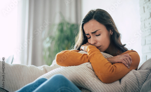 Quadro em tela Sad woman in deep depression is sitting on the couch and crying and thinking abo