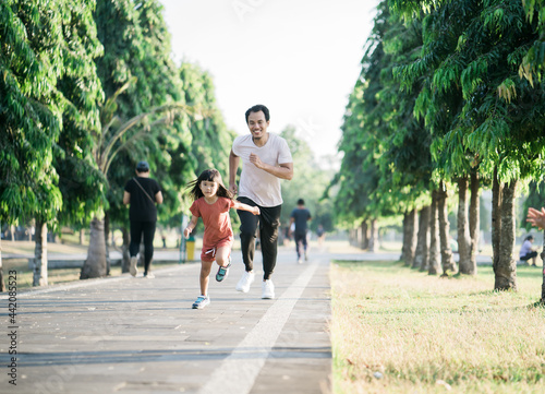father and daughter do exercises running outdoor racing each other. Healthy lifestyle of family with child