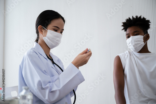 Female doctor or nurse preparing coronavirus 19 vaccination for African-American man waiting to be vaccinated in the laboratory. Concept of preventing the spread of COVID-19.