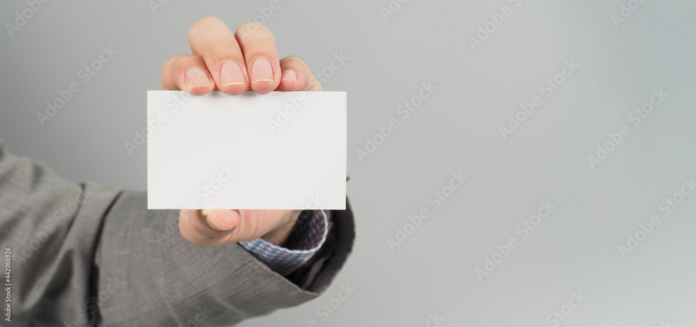 Hand is holding white blank card and wear suit on gray background. business man concept Hand is holding white blank card and wear suit on gray background. business man concept