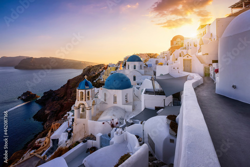 Beautiful sunset view to the idyllic village of Oia, Santorini island, Greece, with the blue domed churches on the edge of the volcanic caldera