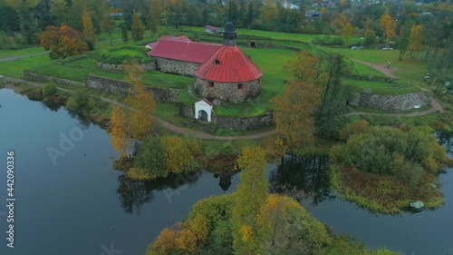 Aerial around stone old Korela fortress Karelia Russia on island of Vuoksa river. Swedish medieval stronghold citadel historical travel landmark. Famous defensive structure. Cloudy foggy. Prison. Film photo