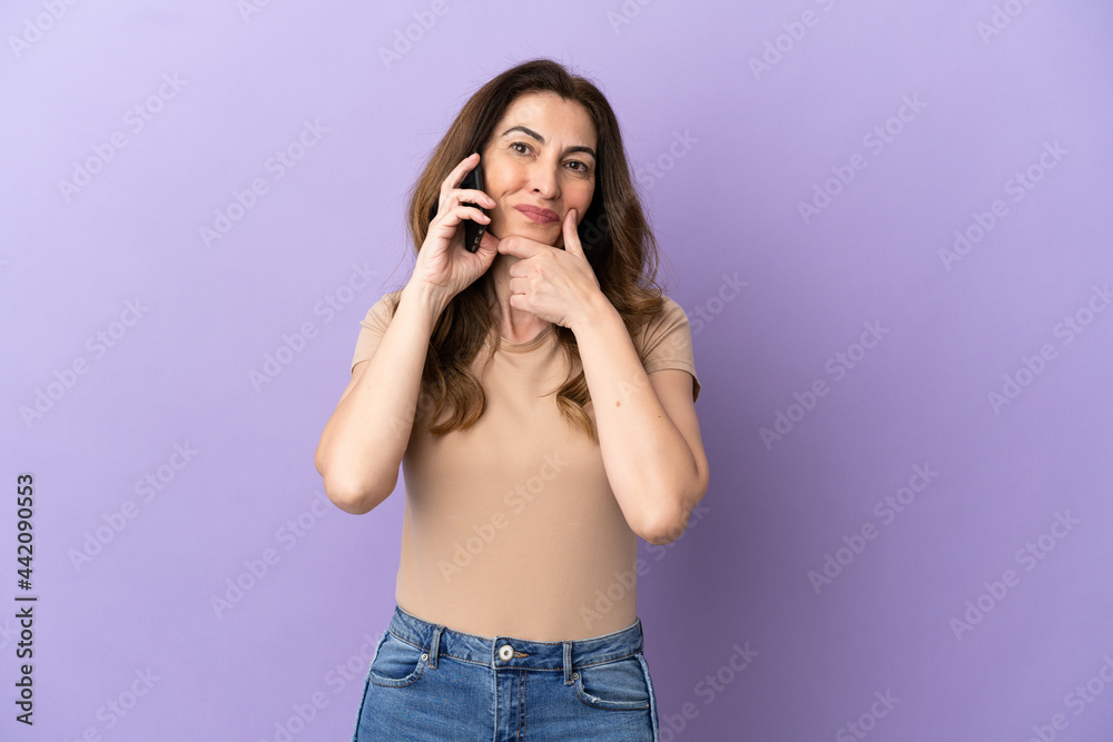 Middle aged caucasian woman using mobile phone isolated on purple background happy and smiling Middle aged caucasian woman using mobile phone isolated on purple background happy and smiling