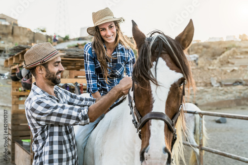 Happy couple of farmers having fun with horse inside corral ranch