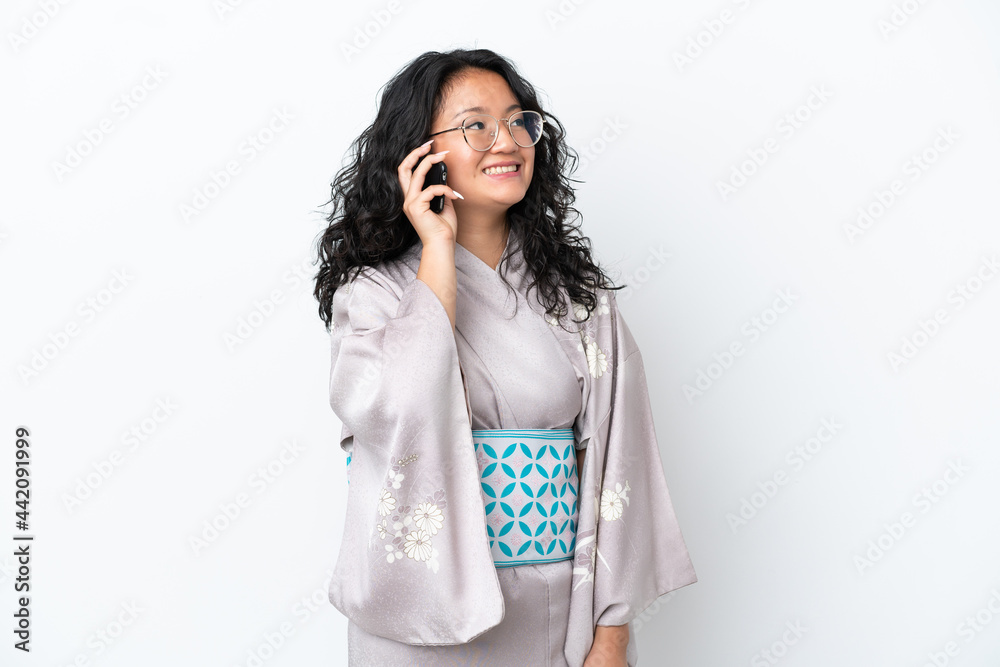 Young asian woman wearing kimono isolated on white background keeping a conversation with the mobile phone Young asian woman wearing kimono isolated on white background keeping a conversation with the mobile phone