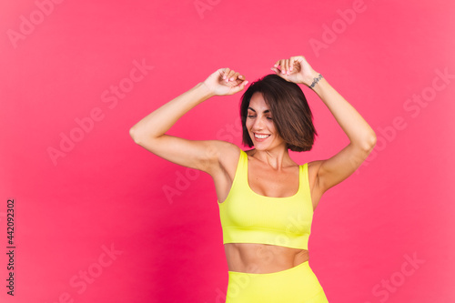 Beautiful fit woman in yellow bright fitting sportswear on pink background happy moving excited perfect body fitness motivation © Анастасия Каргаполов