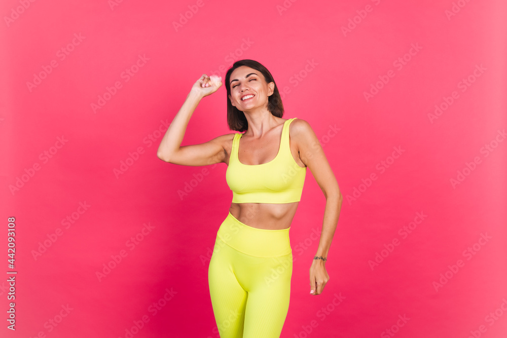Beautiful fit woman in yellow bright fitting sportswear on pink background happy moving excited perfect body fitness motivation Beautiful fit woman in yellow bright fitting sportswear on pink background happy moving excited perfect body fitness motivation