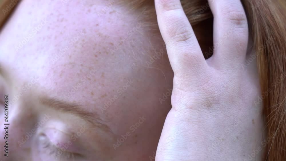 Redhead young girl stroking her hair. Closeup