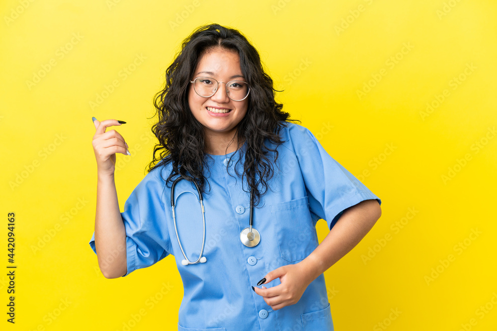 Young surgeon doctor asian woman isolated on yellow background making guitar gesture Young surgeon doctor asian woman isolated on yellow background making guitar gesture