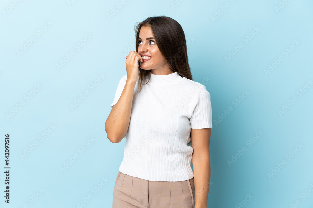 Young Uruguayan woman isolated on blue background is a little bit nervous Young Uruguayan woman isolated on blue background is a little bit nervous