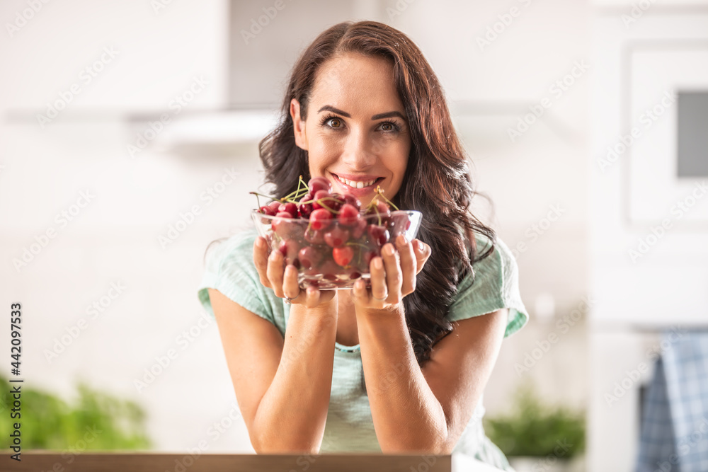 Fresh fruit harvest in the form of cherries in a seethrough bowl held by a woman indoors Fresh fruit harvest in the form of cherries in a seethrough bowl held by a woman indoors