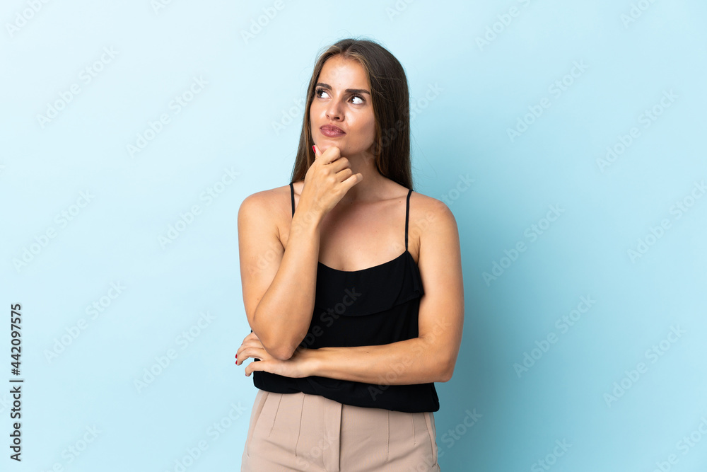 Young Uruguayan woman isolated on blue background having doubts Young Uruguayan woman isolated on blue background having doubts