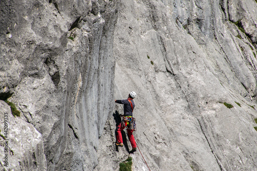 Kletterer hängend an einer Felswand