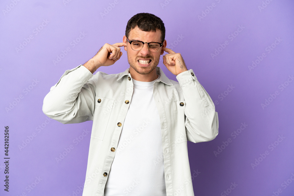 Fototapeta premium Brazilian man over isolated purple background frustrated and covering ears