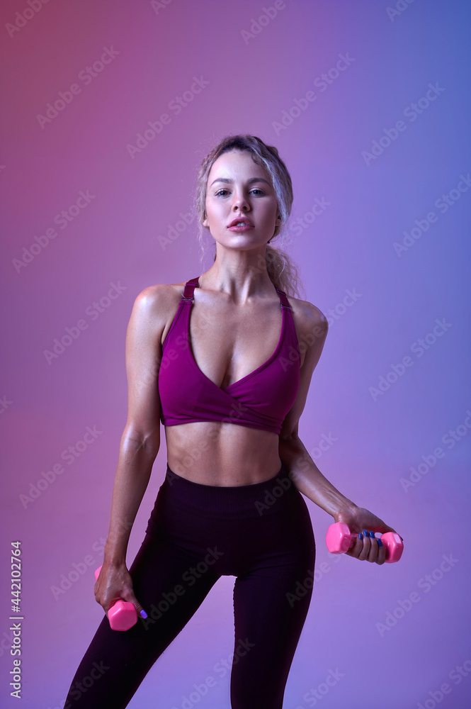Young woman with dumbbells, neon background Young woman with dumbbells, neon background