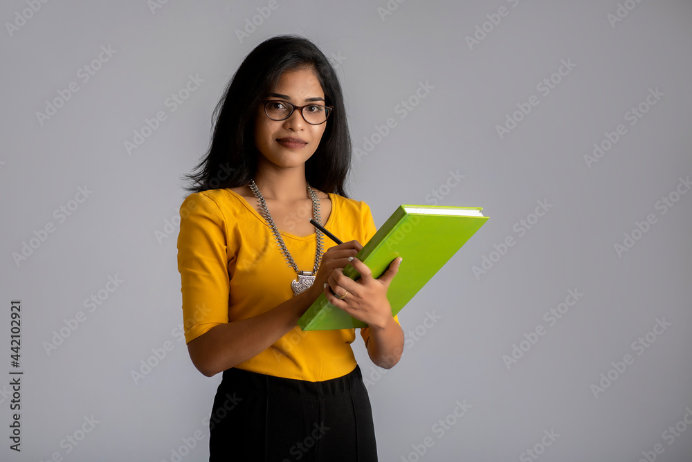 Pretty young girl posing with the book on grey background Pretty young girl posing with the book on grey background