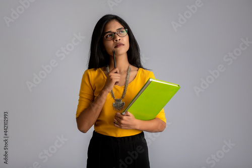 Pretty young girl posing with the book on grey background