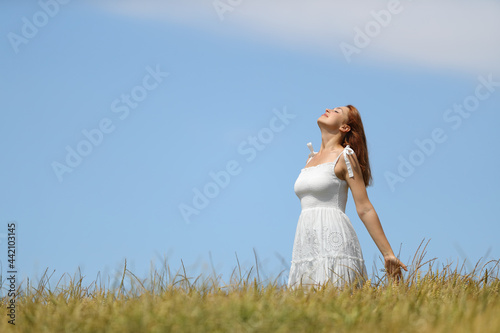 Woman with white dress breathing fresh air in a wheat field