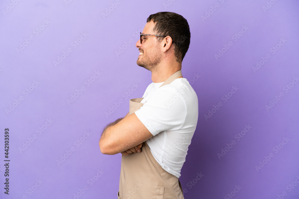 Brazilian restaurant waiter over isolated purple background in lateral position Brazilian restaurant waiter over isolated purple background in lateral position