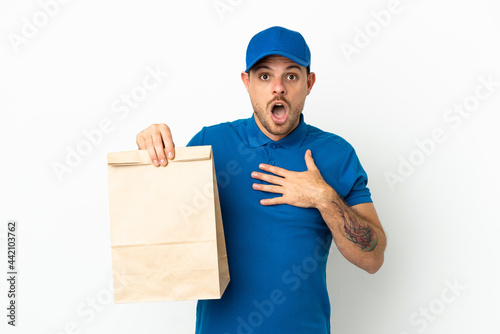 Brazilian taking a bag of takeaway food isolated on white background surprised and shocked while looking right